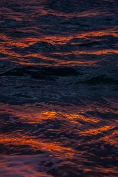 Sunset light reflections on ocean surface with vivid orange tones Stock Photos