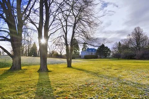 Sunset with light snowfall in springtime in the backyard of a mansion. Stock Photos