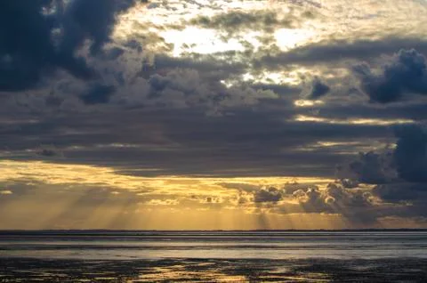Sunset light through the clouds from the beach, Bay of Saint Michel in Norman Stock Photos