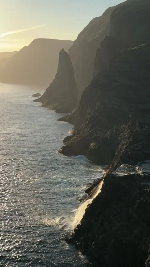 Sunset lights the cliffs of Vágar Island, Faroe Islands, with Trøllkonufingur  Stock Footage 310947915