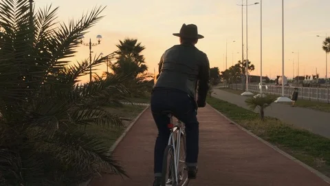 At sunset, a man stylishly dressed riding a Bicycle. A man in a leather jacket 스톡 동영상 121810140
