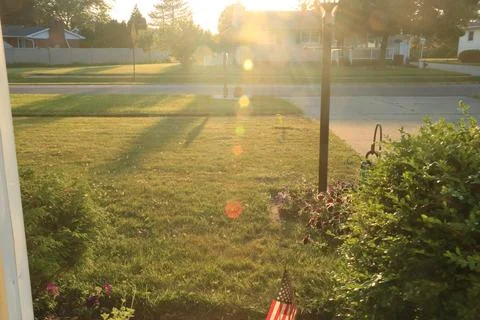 Sunset more bokeh behind light post with small American flag 库存照片