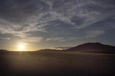 Sunset in the mountains with sunrays over a field 스톡 사진