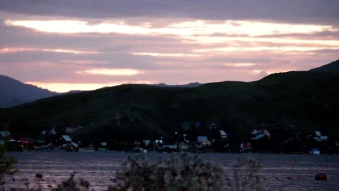 Sunset, mountains, water and small houses on the shore, with a seagull. Stock Footage 111198568