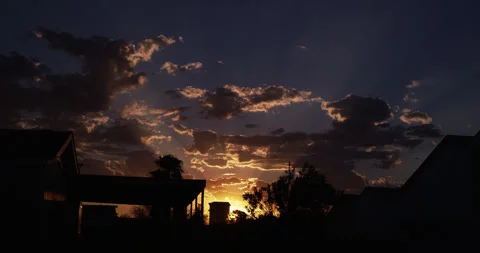 Sunset from a nondescript neighborhood of silhouetted rooftops. Vídeos de archivo 283438563