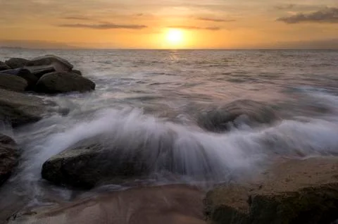 Sunset Ocean Beach Wave Breaking on Rocks Stock Photos