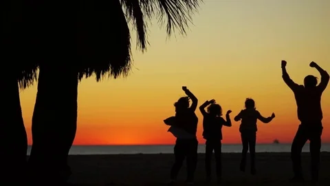Sunset on the ocean. Dancing silhouettes of parents and their children Stock Footage 82784089