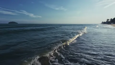 Sunset ocean waves roll onto sandy shore with palm trees and distant islands Video stock 331042223