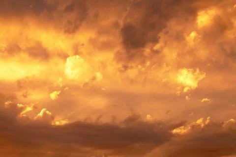 Sunset or dawn sky, yellow clouds with rays and hidden sun. Heaven high Stock Photos