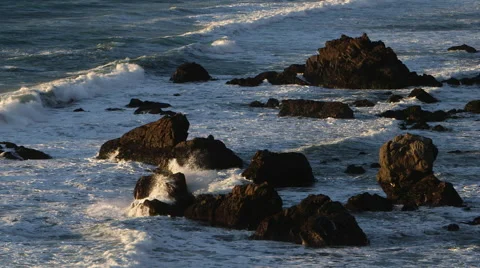 SUNSET OR SUNRISE LIGHT ON ROCKS AS OCEANS WAVES CRASH; WIDE Stock Footage 59070970