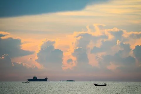 Sunset orange cloud back on dark silhouette sky and fishing boat on sea Stock Photos