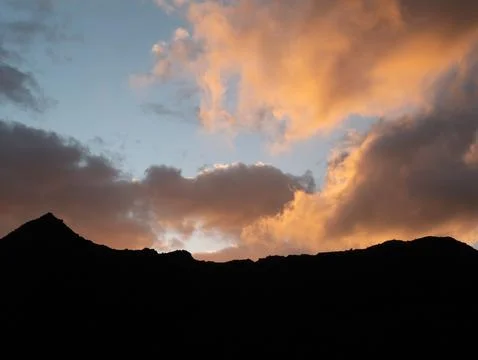 Sunset orange clouds rolling over mountain. Stock Photos