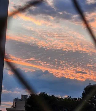 Sunset with an orange sky and fluffy clouds Stock Photos