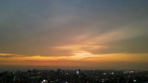 Sunset with an orange sky over a big city full of buildings and lights Stock Footage 296990812