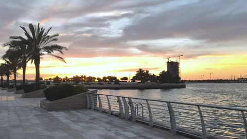 Sunset Over Al Raha Beach, Abu Dhabi with Palm Trees and Waterfront Promenade Видео 338376774
