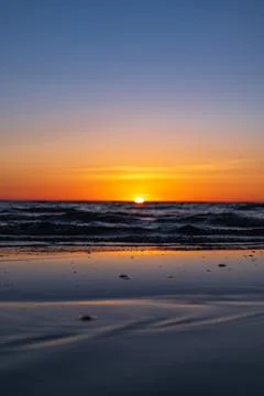 Sunset over Baltic waves and wet shore near Lithuanian coastline Stock Photos
