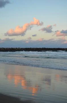 Sunset over a beach with a break wall Stock Photos