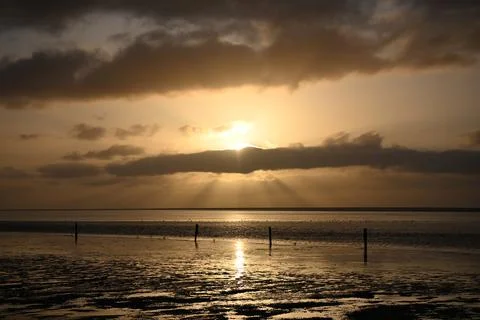 Sunset over the beach with clouds and reflections on the water at low tide 库存照片