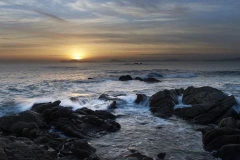 Sunset over the beach with large rocks Stock Photos