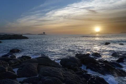Sunset over the beach with large rocks Stock Photos