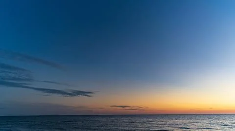 Sunset over beach looking at horizon over water against epic sky 写真素材