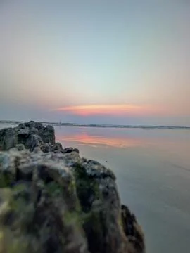 Sunset over the beach with rocks in the foreground showing colors reflectin.. Stock Photos