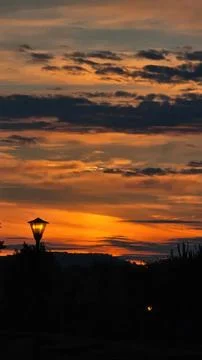 Sunset over beach with sky clouds and a lamp post silhouette Stock Photos
