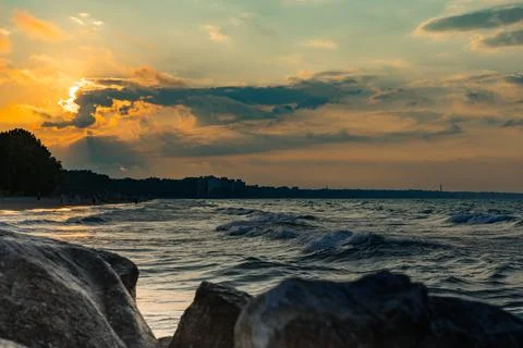 Sunset over the beach with waves and rocks along the shore in summer near a.. Stock Photos