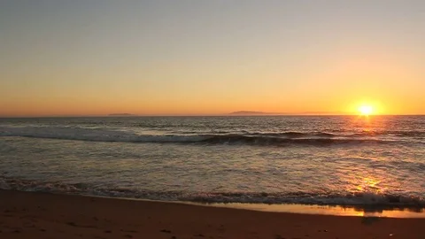 Sunset over the beach as waves wash gently at low tide Stock Footage 72873582