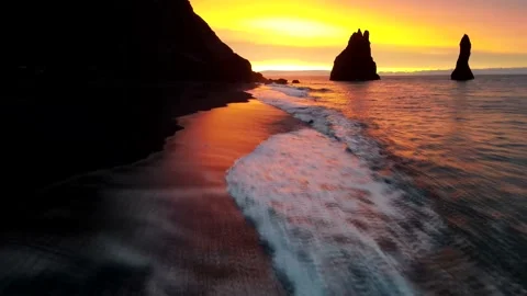 Sunset over Black Sand Beach and the Reynisdrangar Sea Stavks. 4K Drone footage Stock Footage 142003466