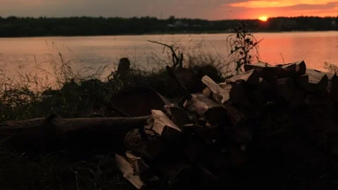 Sunset Over Calm and Still Water, With a Piled Stack of Firewood Nearby Stock Footage 313599234