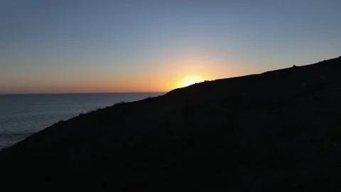 Sunset Over Calm Atlantic with Dark Coastline and Distant Pier Gran Canaria Stock Footage 309940506