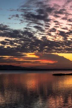 Sunset Over Calm Lake with Dramatic Clouds Stock Photos