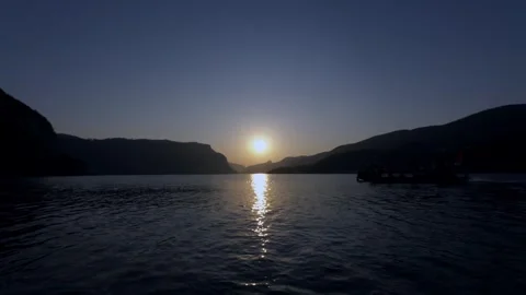 Sunset over a calm lake with mountains and a boat Stock Footage 341925938