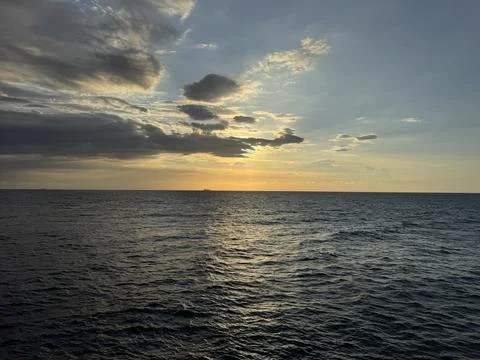Sunset Over Calm Ocean with Dramatic Clouds Stock Photos