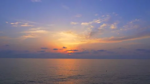 Sunset over calm ocean, featuring soft hues of orange, pink, and purple blending Stock Footage 295171559