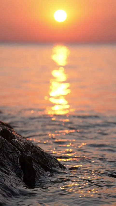 Sunset Over Calm Ocean With Golden Reflection and Rocky Shoreline at Golden Hour Stock Footage 337413605