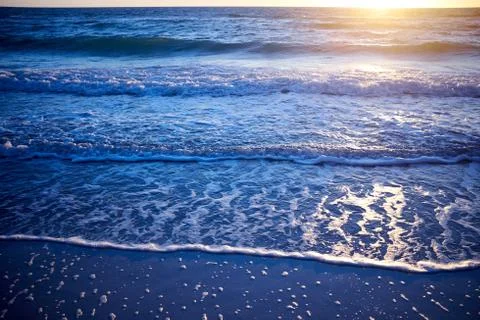 Sunset over a calm ocean with lapping waves Foto stock