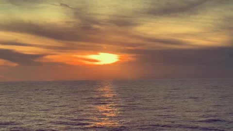 Sunset Over a Calm Ocean with Soft Clouds in the Sky and Gentle Waves on th.. Stock Footage 338281699