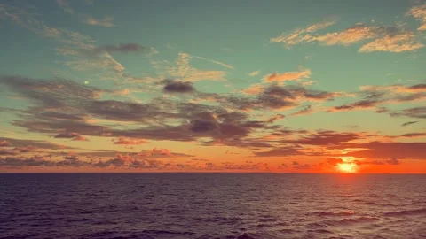 Sunset over a calm ocean with vibrant clouds creating a serene and pictures.. Stock Footage 338281665