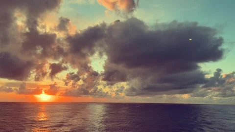 Sunset over a calm ocean with vibrant clouds creating a dramatic sky as sun.. 動画素材 338282599