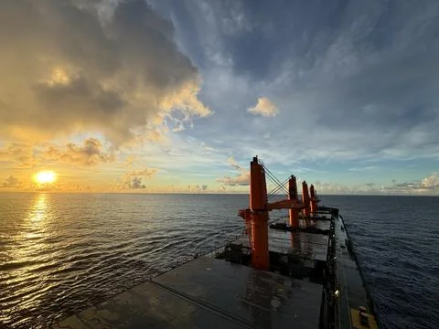 Sunset over calm ocean viewed from ship deck with dramatic clouds Foto stock