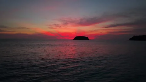 Sunset over calm ocean water with silhouetted island in the distance Stock Footage 336926755