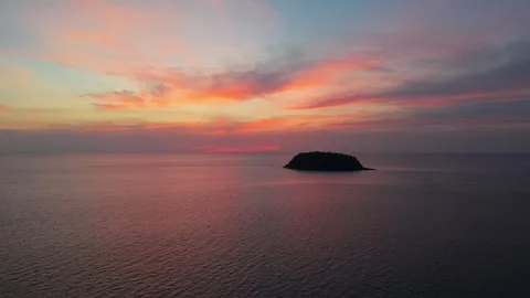 Sunset over calm ocean waters with distant island silhouette and colorful sky Stock Footage 337020124