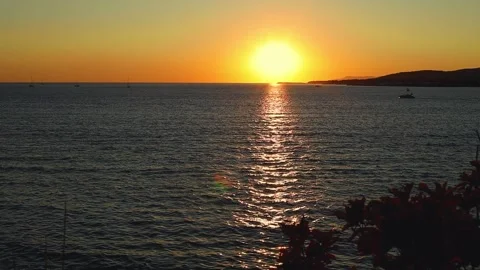 Sunset over calm ocean waters with silhouettes of distant hills and boats Stock-Footage 344813516