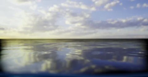 Sunset over calm ocean waters with reflection of clouds and sky Ilustração Stock