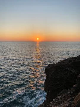 Sunset over calm ocean waters with golden reflections Stock Photos