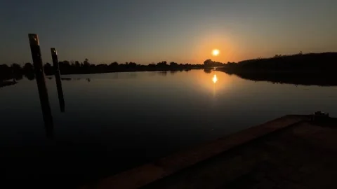 Sunset over calm river with reflections and mooring posts Stock Footage 343701209