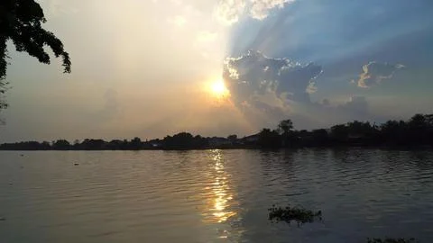 Sunset over calm river with trees and cloudy sky Stock Photos