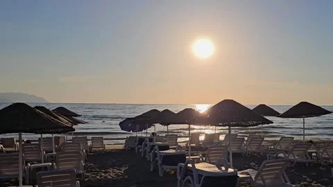 Sunset over calm sea with empty beach chairs and umbrella silhouette  Stock-Footage 337402070
